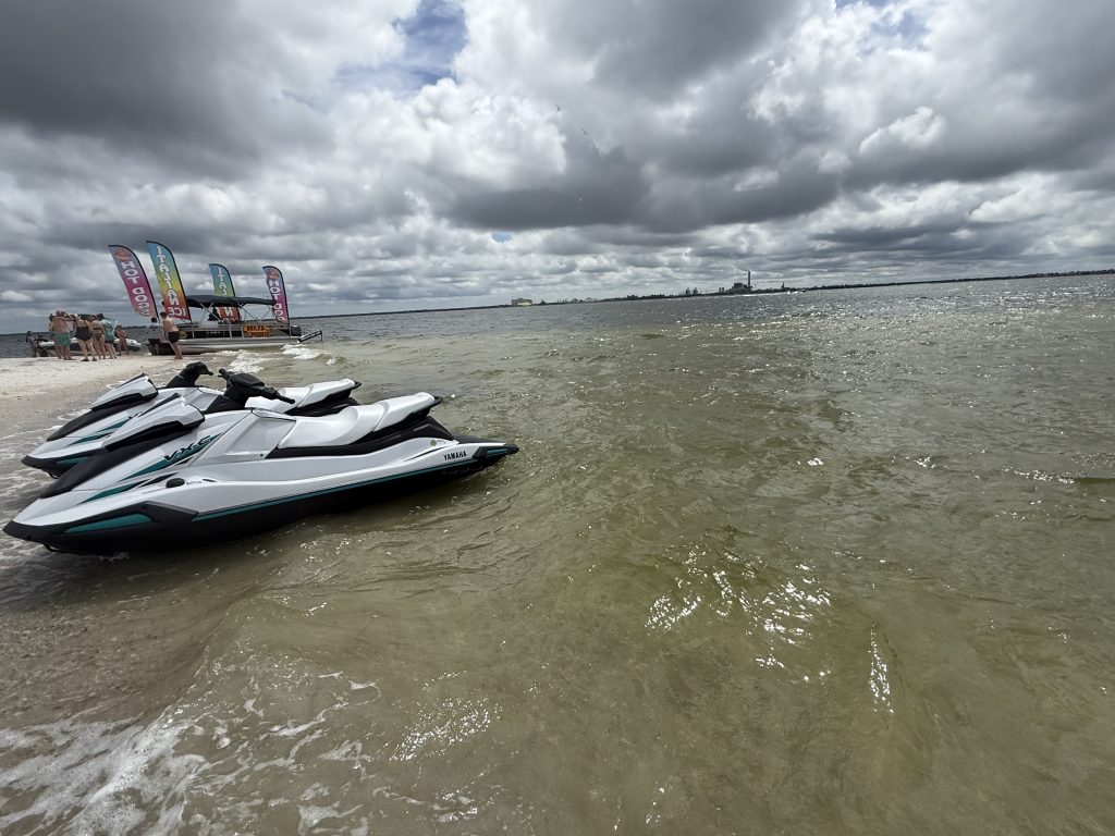 Jet skis lined up on the sandy beach in Tampa Bay, ready for rental with Southern Dreams Watersports.