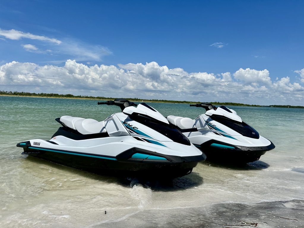 Jet skis lined up on the sandy beach in Tampa Bay, ready for rental with Southern Dreams Watersports.