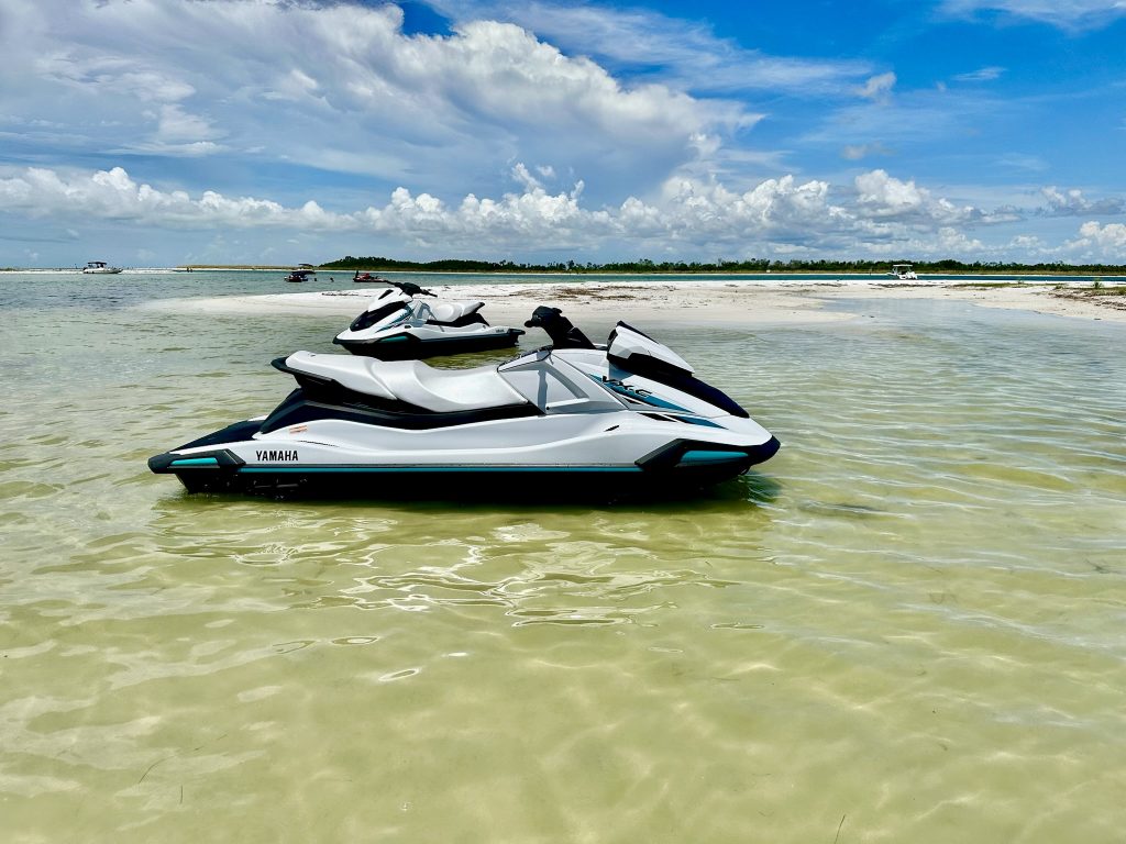 Jet skis lined up on the sandy beach in Tampa Bay, ready for rental with Southern Dreams Watersports.